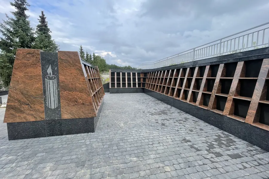 Granito kolumbariumas — nišų siena ir stela su graviruota žvake