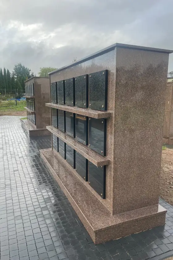 Laisvai stovintis kolumbariumo modulis su granito lentynėlėmis po nišų eilėmis
